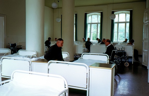 Patienten sitzen in einem Bettensaal