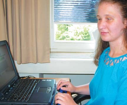 Anika Laskiewicz am Laptop mit einer Braillezeile. Er ermöglicht der Verwaltungsangestellten Texte zu lesen